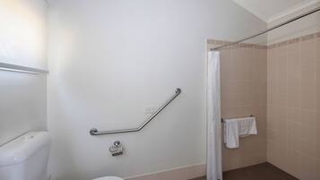 Un baño con inodoro, barra de apoyo, cortina de ducha y toallero.