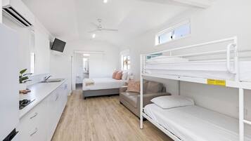 Una habitación compacta y moderna con literas, kitchenette y ventilador de techo.