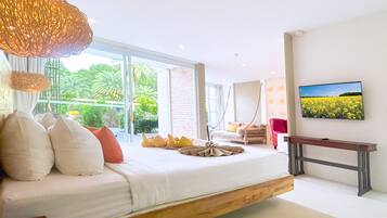 A modern bedroom with a large bed, a wooden platform, a TV, and a view of a yellow flower field.
