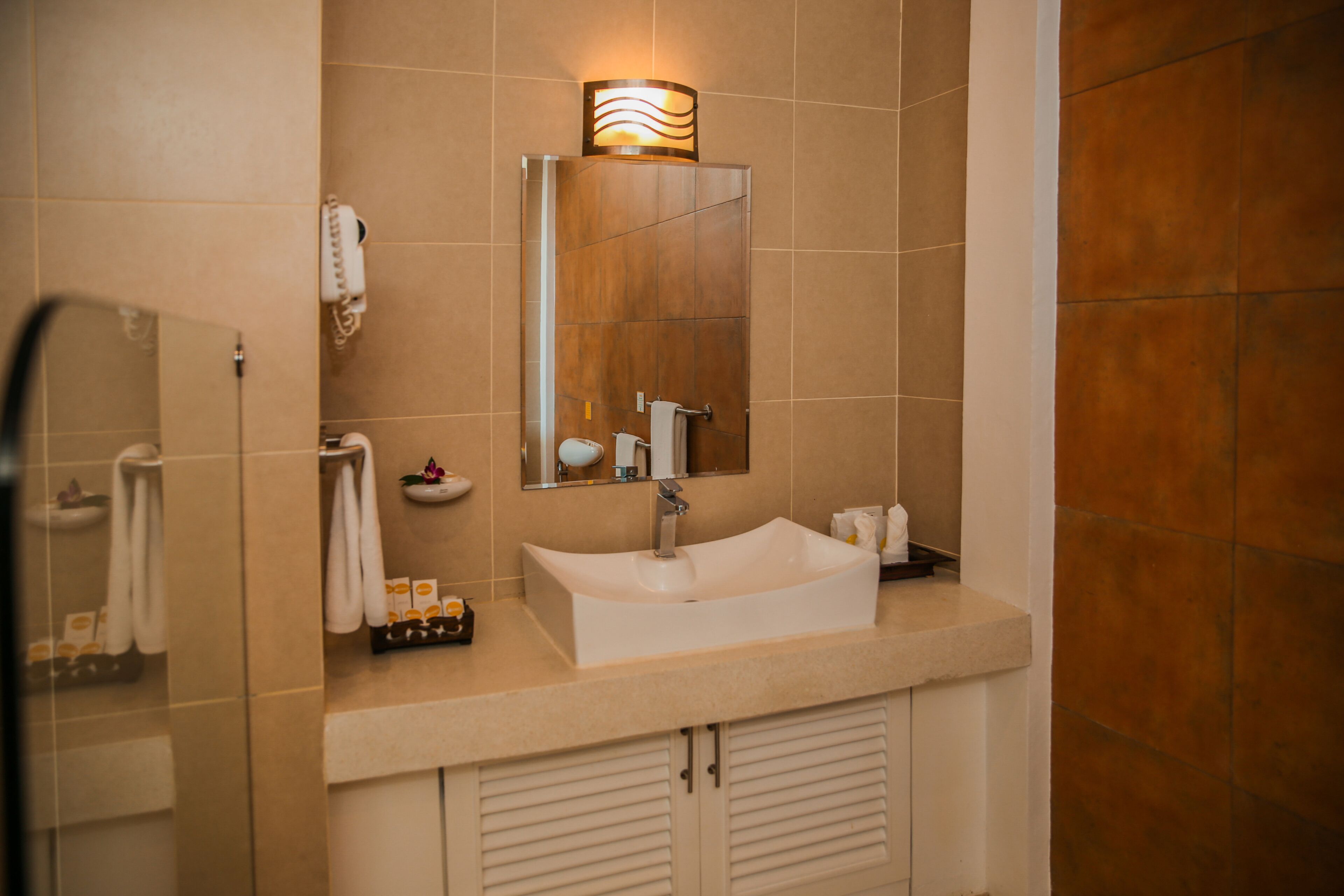A bathroom with a white sink, a mirror, a towel rack, and a wall-mounted light fixture.