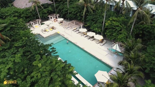 An aerial view of a resort with a rectangular swimming pool surrounded by lounge chairs and umbrellas, set in a tropical environment with dense greenery. - Summer Luxury Beach Resort and Spa (Ko Pha-ngan)