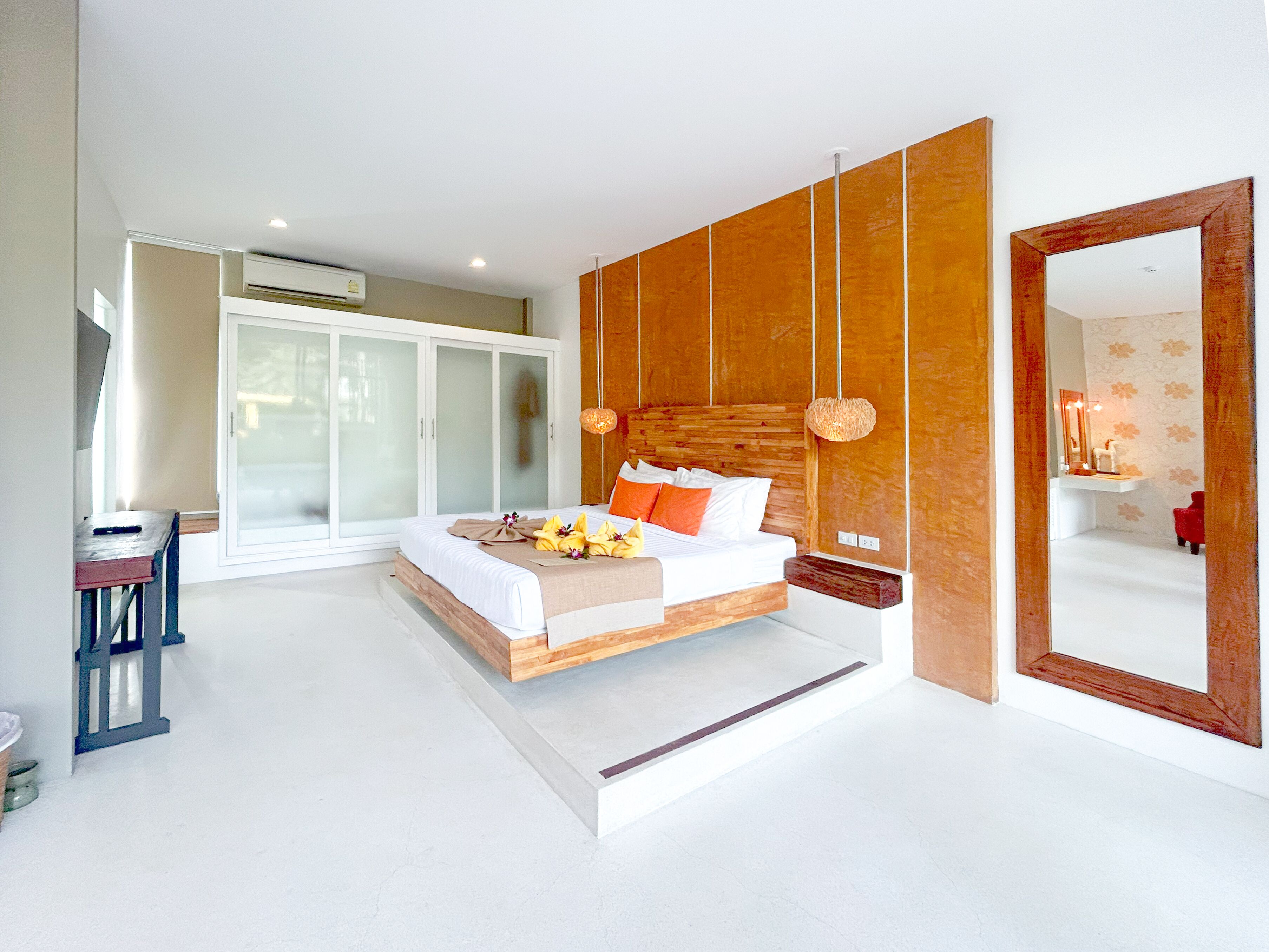 A modern bedroom with a large bed, a wardrobe, and a mirror.
