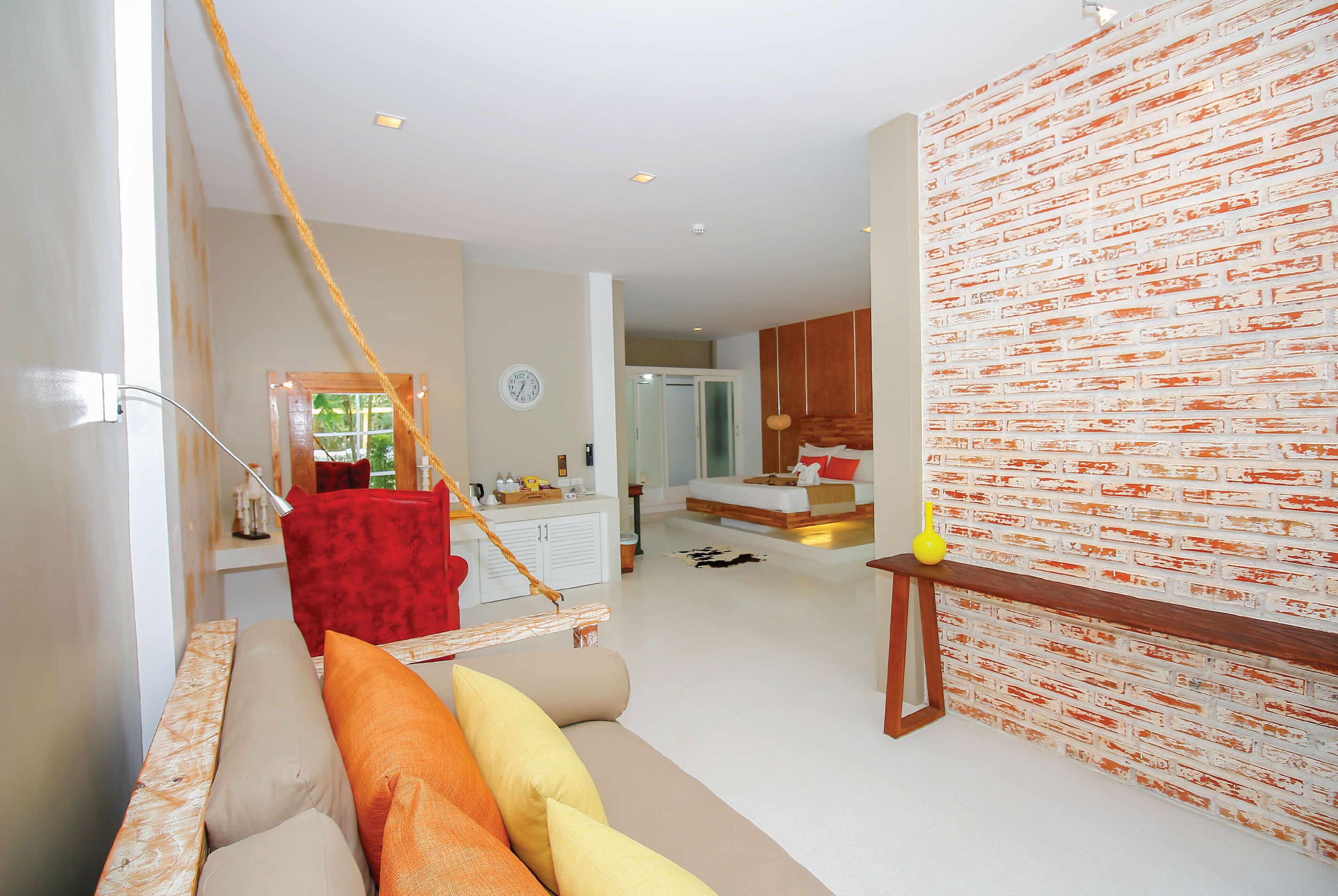 Una sala de estar moderna con un sofá, una silla roja, un banco de madera y una pared con diseño de ladrillo.