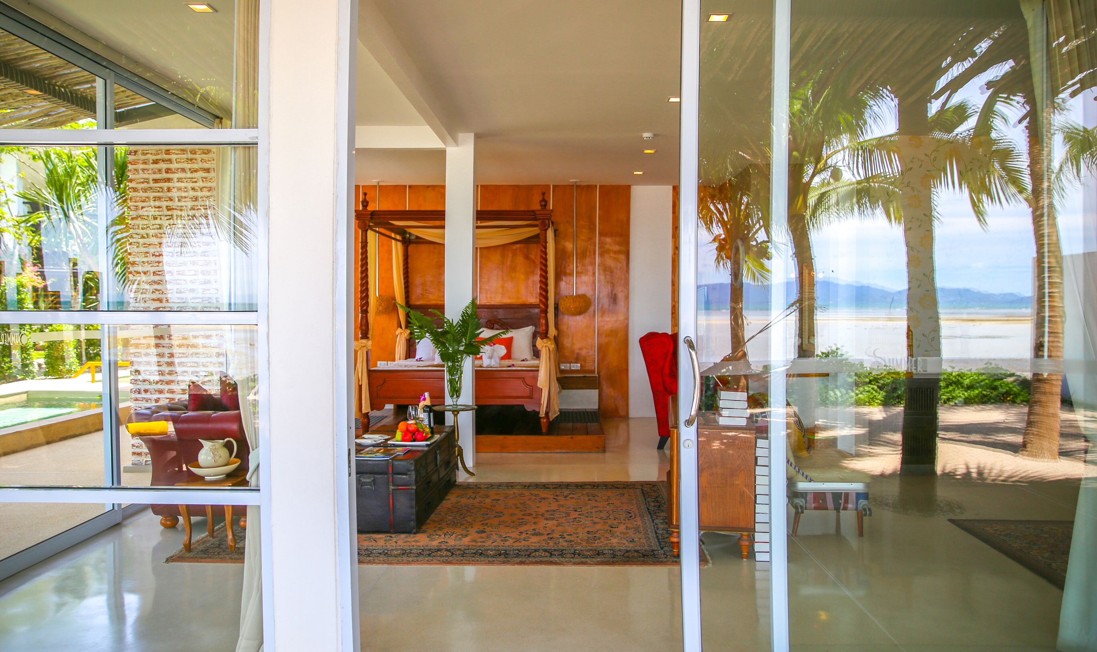 A modern hotel room with a large glass door leading to a balcony with a view of the beach.