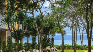 A pathway lined with trees and rocks, leading to a grassy area with a statue. - Summer Luxury Beach Resort and Spa (Ko Pha-ngan)