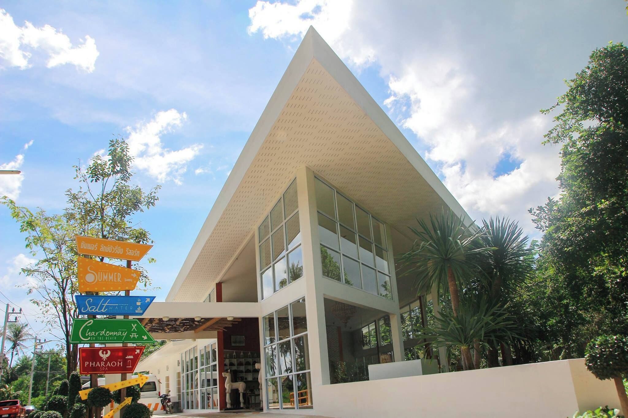 A modern building with a triangular roof and large windows. There are signs indicating amenities such as a spa and a restaurant.