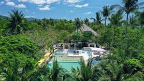 A pool area with lounge chairs and a thatched-roof structure surrounded by lush greenery. - Summer Luxury Beach Resort and Spa (Ko Pha-ngan)