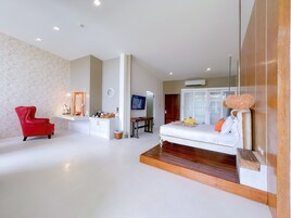 Ein modernes Schlafzimmer mit einem großen Bett, einem roten Sessel, einem Schreibtisch und einem Schminktisch.