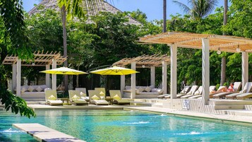 Una piscina al aire libre, sombrillas, sillones reclinables de piscina