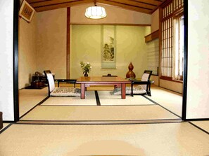Una habitación japonesa tradicional con suelo de tatami, una mesa baja y un panel shoji.