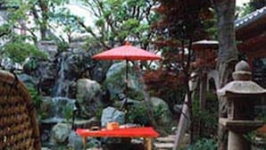 A traditional Japanese garden with a red table and umbrella, stone lantern, and a stone path. - Ise Todaya Ryoan (Ise)