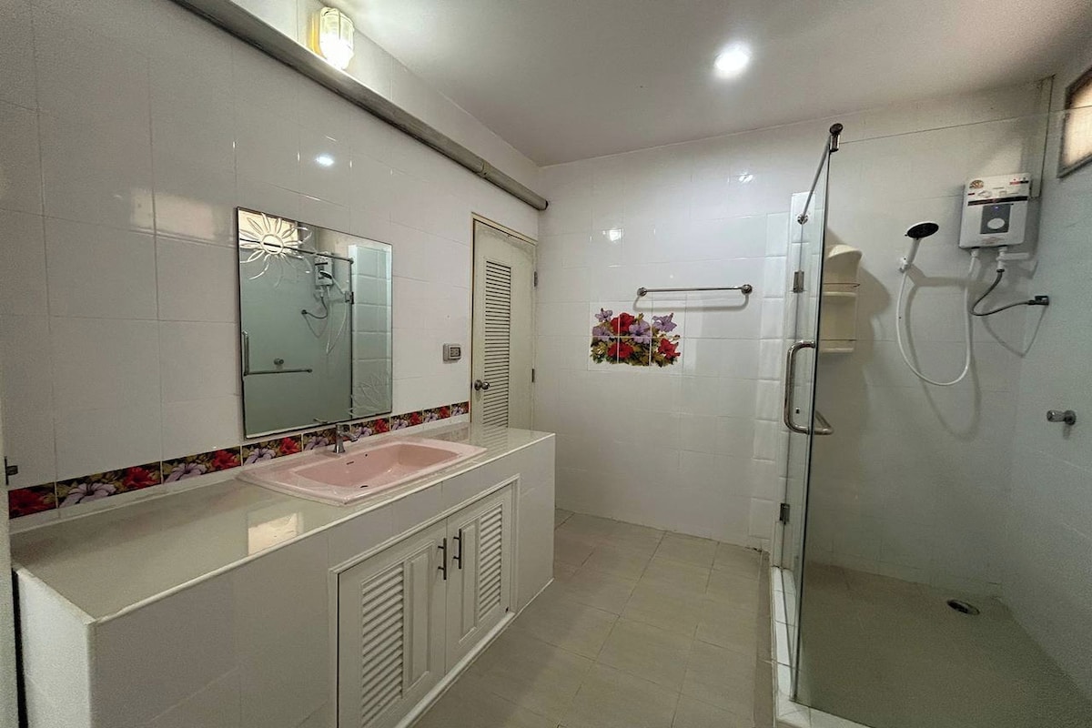 Un baño con lavamanos blanco, espejo y ducha.