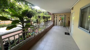 A corridor with a tiled floor, a white railing, and potted plants along the left side. - U.D.Home Apartment (Ban Chang)