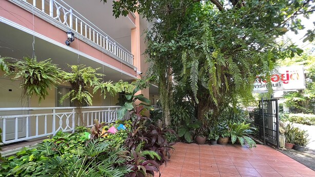 A hotel entrance with a tiled walkway, potted plants, and a balcony with a railing. - U.D.Home Apartment (Ban Chang)