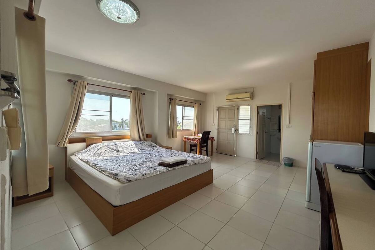 A spacious bedroom with a large bed, a dining area, and a kitchenette.