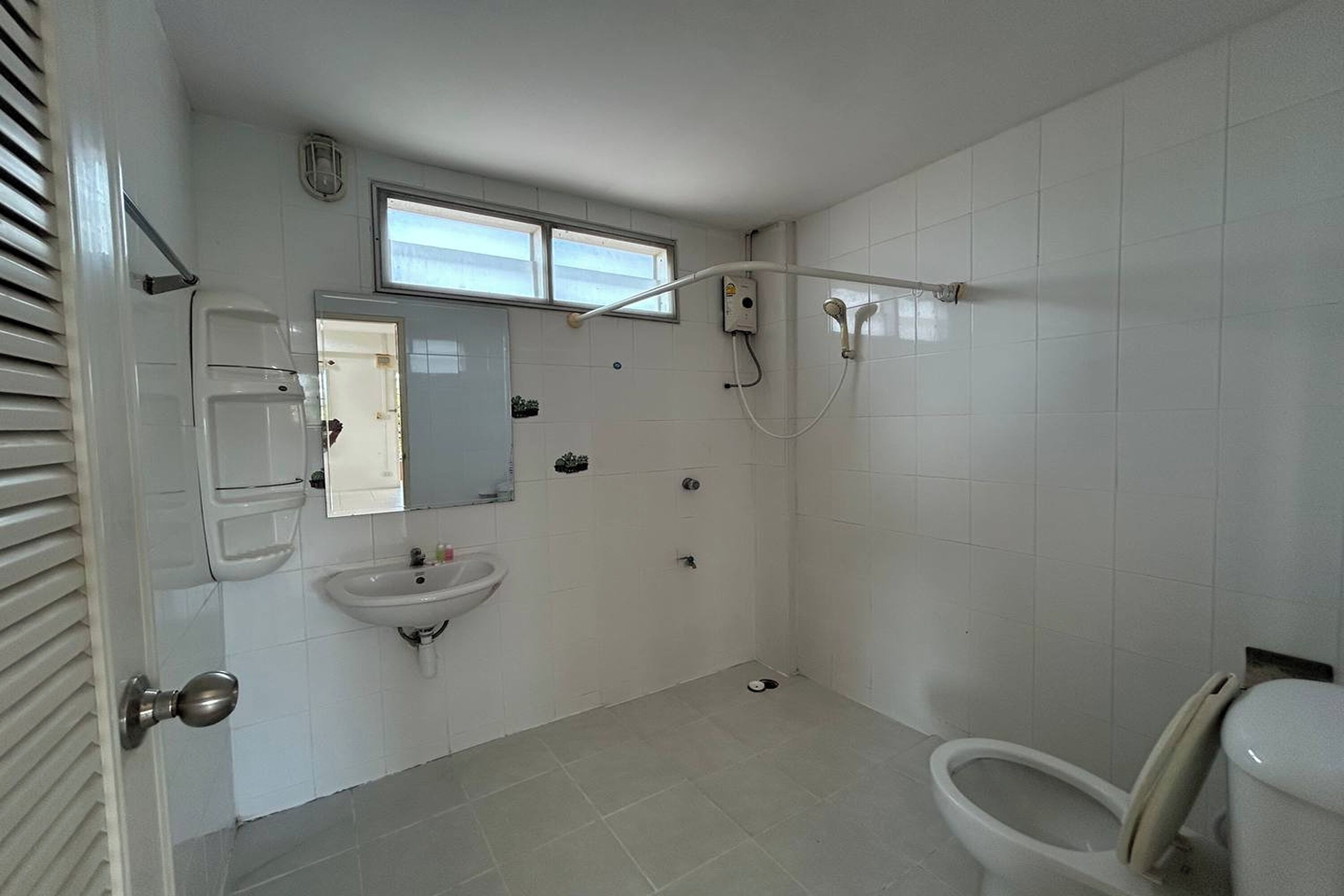 Casa de banho com sanita, lavatório e chuveiro.