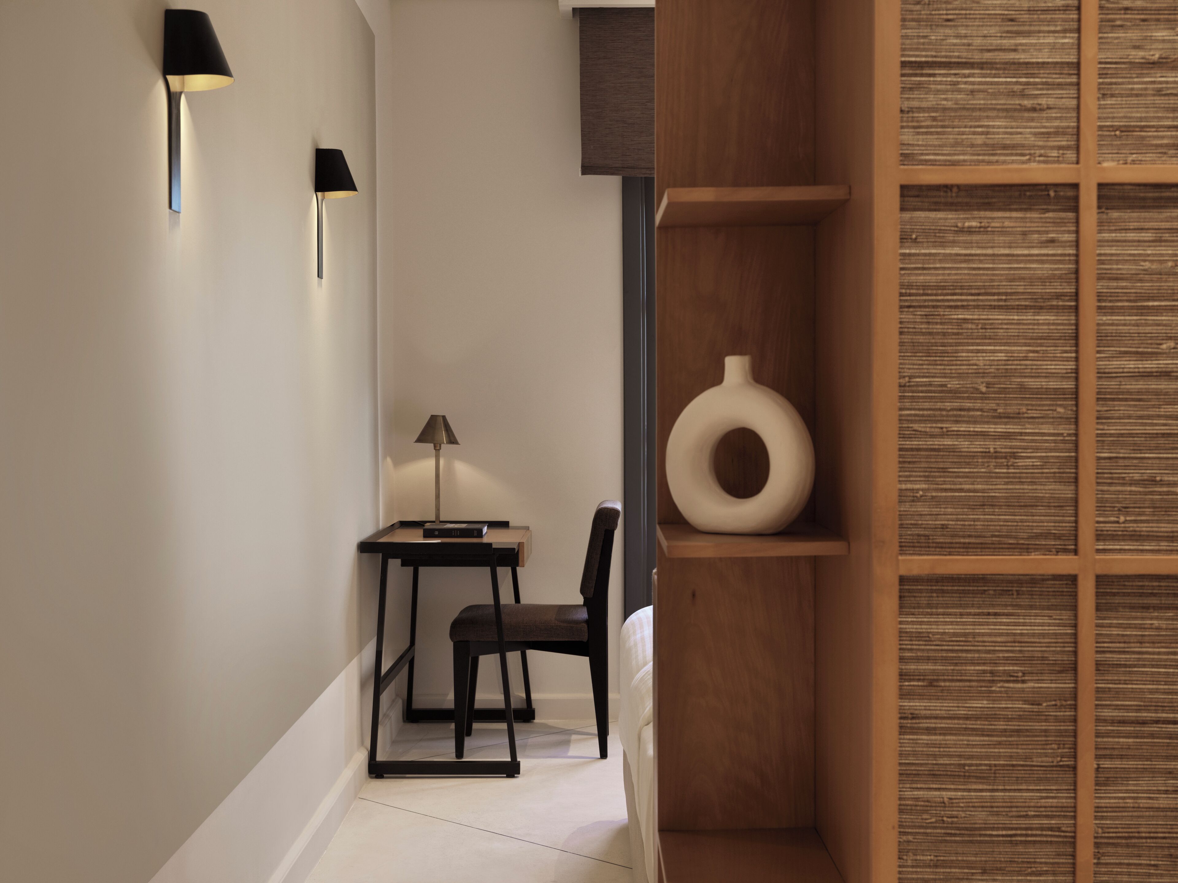 A modern hallway with a desk, chair, and a decorative wooden shelf.