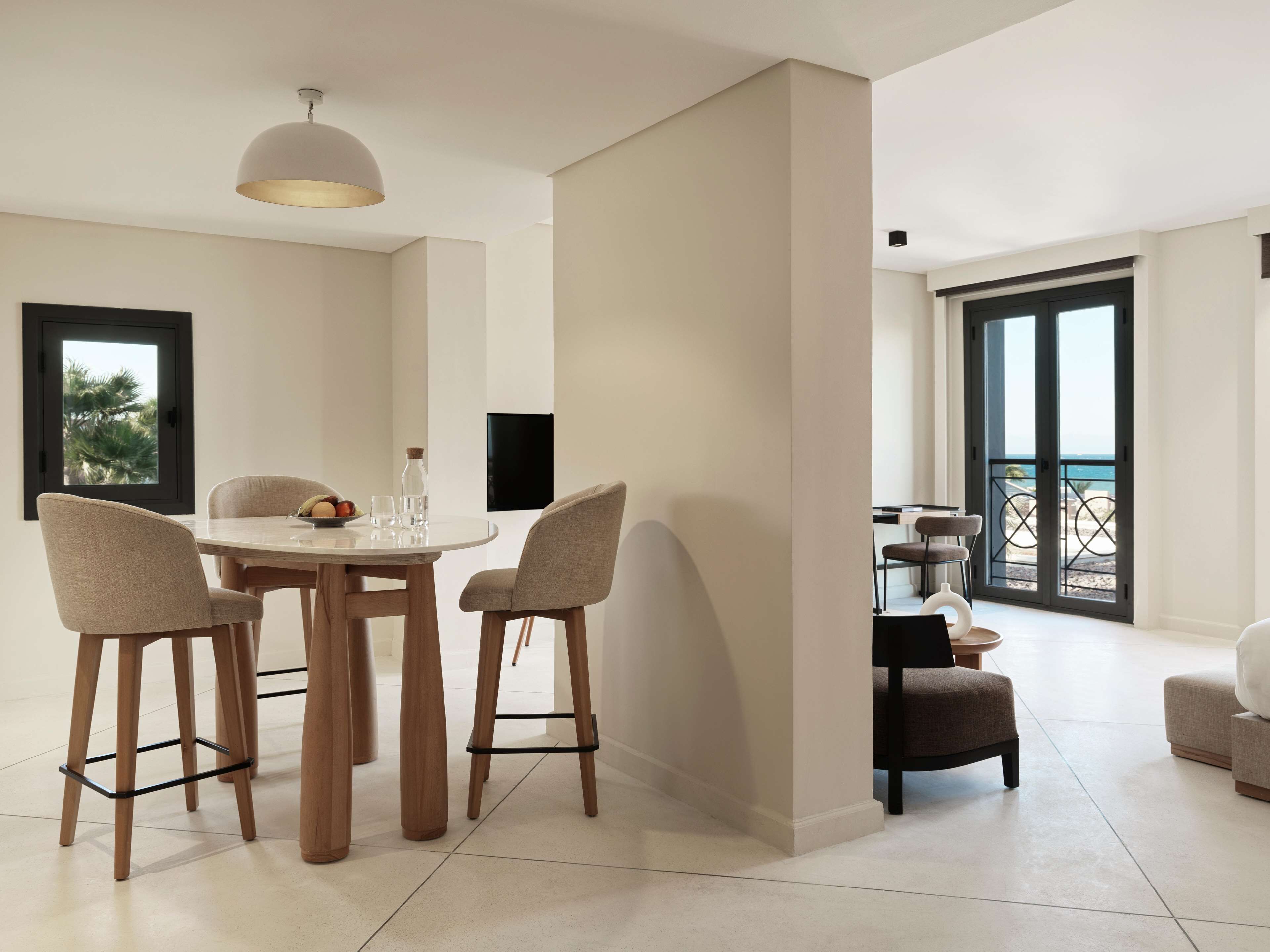 Un espace repas moderne avec une table ronde, quatre chaises et un luminaire suspendu.