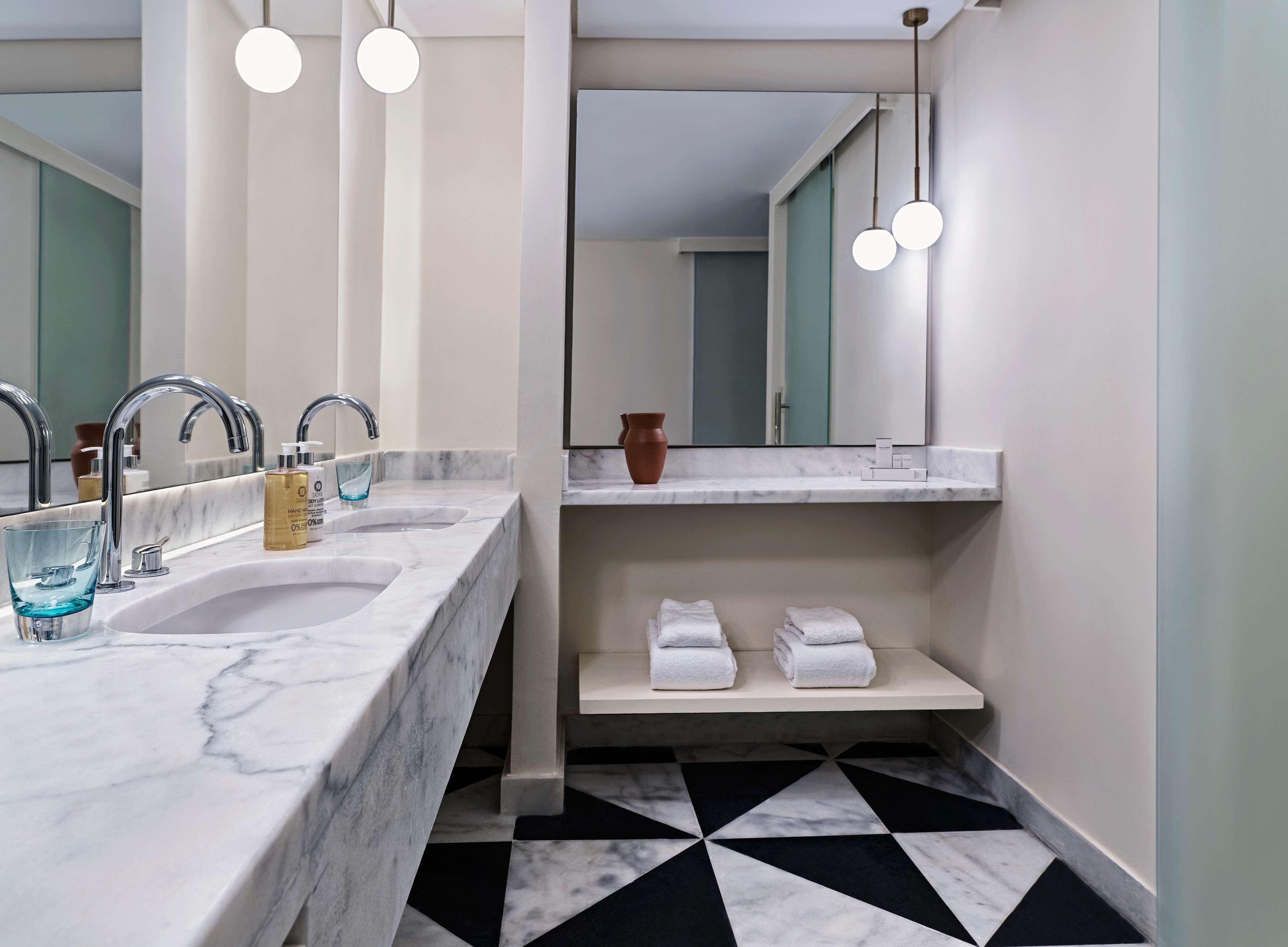 A modern bathroom with two sinks, a large mirror, and a black and white patterned floor.