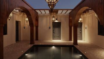 A pool area with wooden arches and a central door, surrounded by walls with recessed lighting.