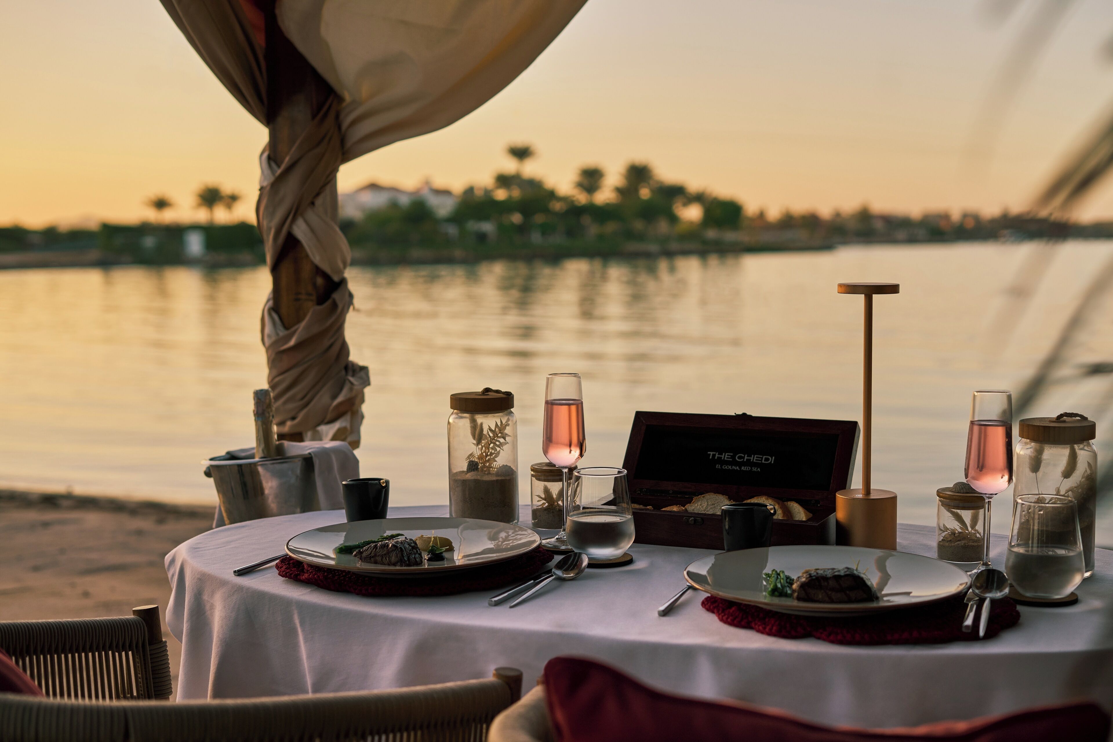 A table set for a meal with a view of the water and trees in the background.