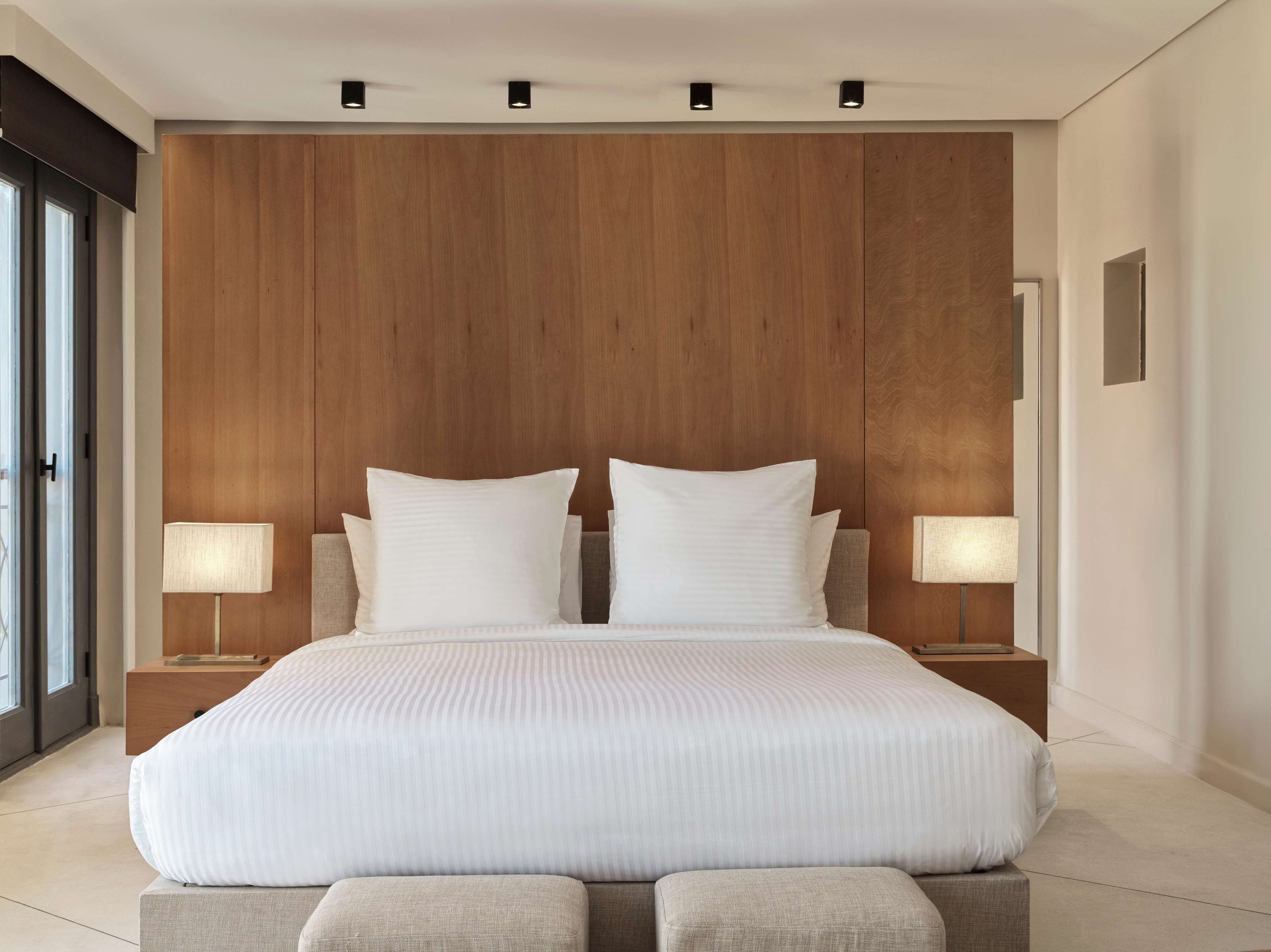 Ein modernes Schlafzimmer mit einem großen Bett, zwei Nachttischen und einem Holz-Kopfteil.