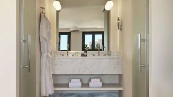 Un baño moderno con un espejo grande, dos lavamanos y una cabina de ducha de vidrio.