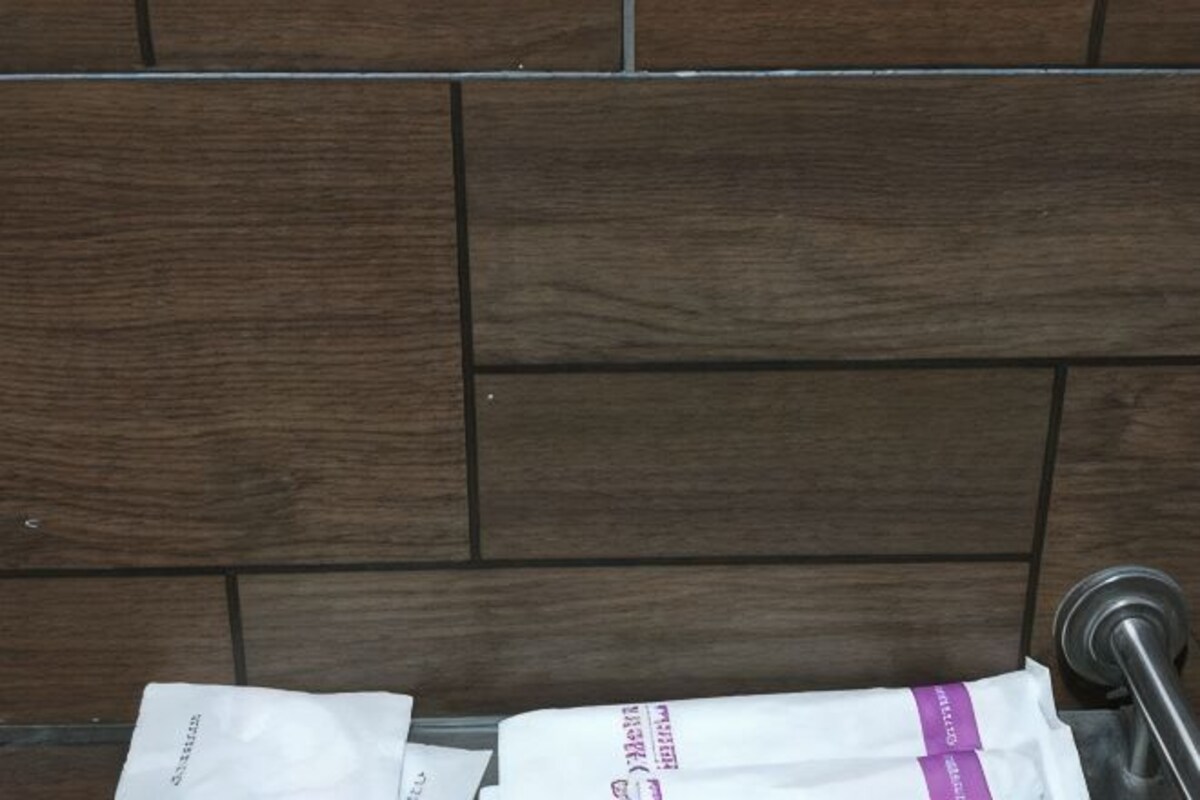 A tiled wall with a metal handle and a white object with purple text.