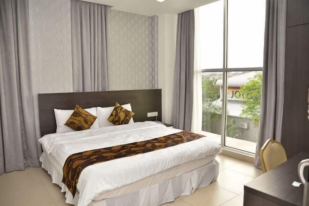Habitación de hotel con una cama grande, un escritorio y vistas al exterior.