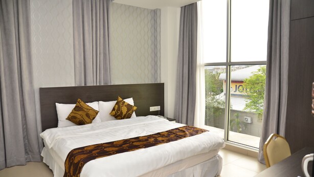 Een hotelkamer met een groot bed, een bureau en uitzicht op een gebouw.