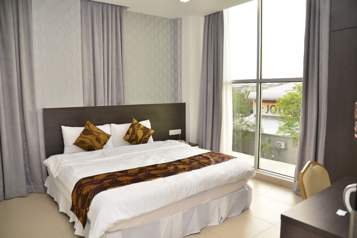 Habitación de hotel con una cama grande, un escritorio y vistas a un edificio.