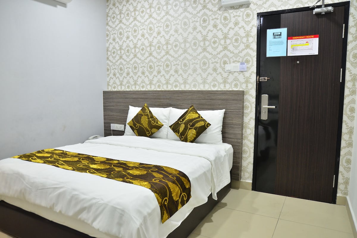 Una habitación de hotel con una cama, una puerta y una pared con papel tapiz estampado.