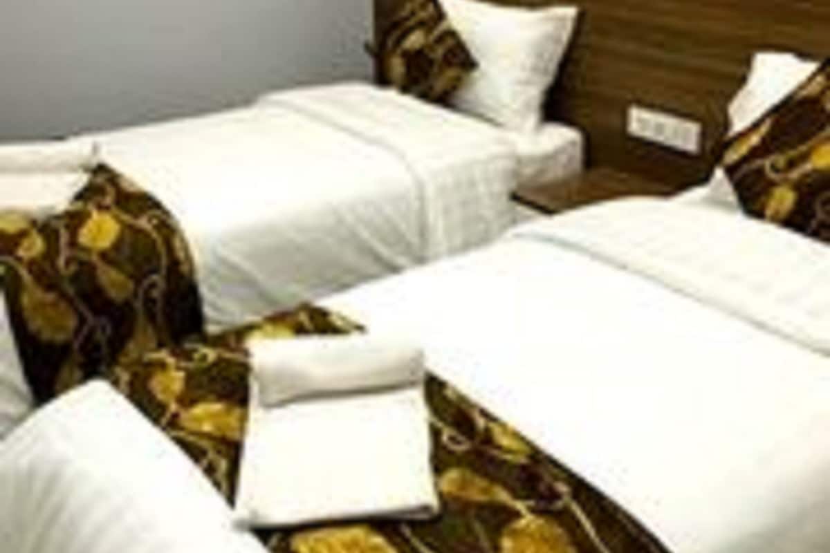 Habitación de hotel con dos camas, cada una con ropa blanca y almohadas decorativas.