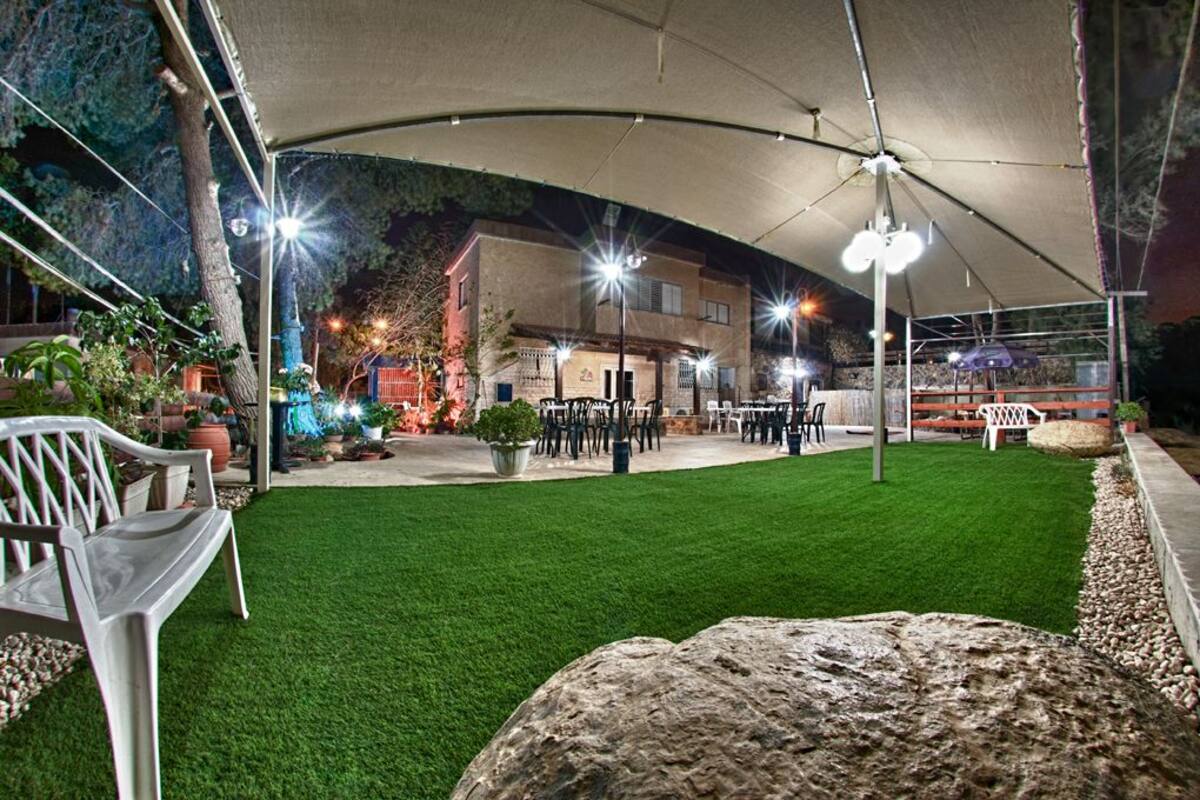 Un espacio de patio al aire libre con un dosel curvo, césped artificial verde y mobiliario exterior.
