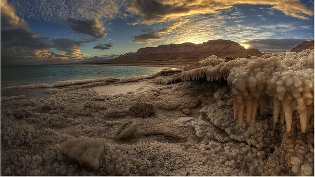 Een strand met unieke geologische formaties en een ondergaande zon.