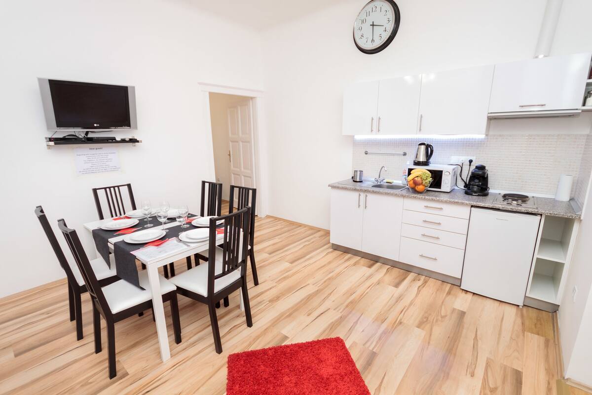 A compact kitchen with white cabinets, a microwave, a coffee maker, and a toaster.