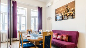 Un comedor con una mesa de madera, sillas tapizadas en azul y un sofá púrpura.