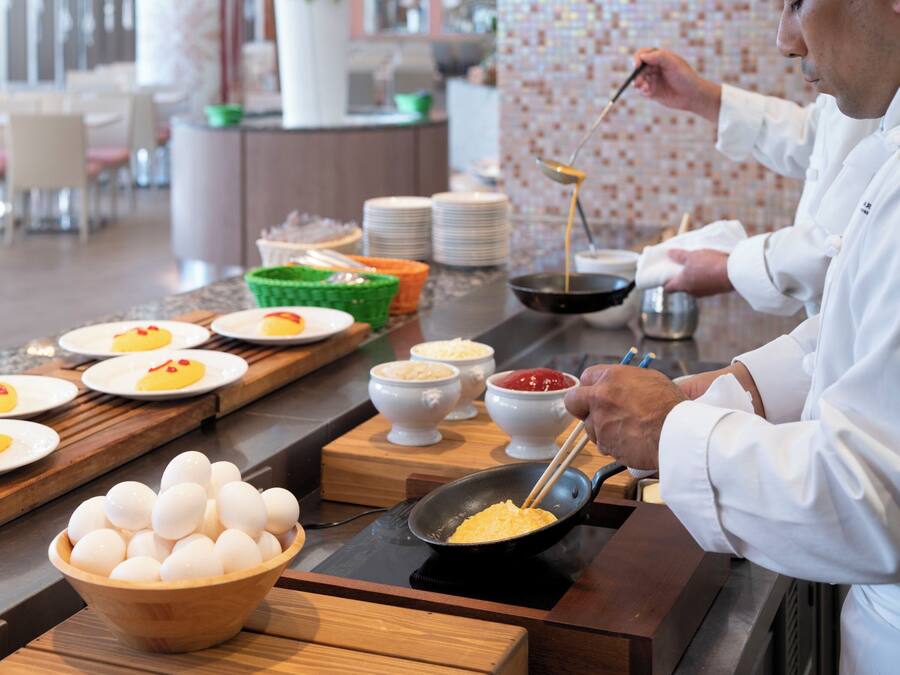A chef preparing food in a kitchen with a variety of dishes and ingredients on the counter.