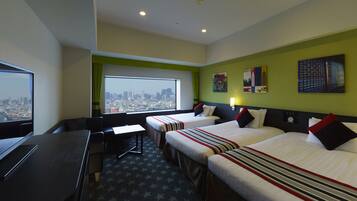 Habitación de hotel con dos camas, un escritorio y un amplio ventanal con vistas a la ciudad.