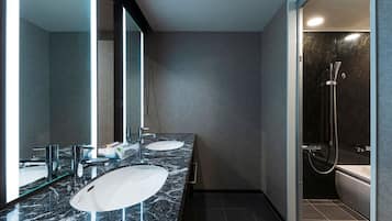 A modern bathroom with two sinks, a large mirror, and a shower area.