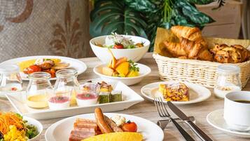 Un bufé de desayuno con diversos platos, como huevos, tocino, salchichas y bollería.