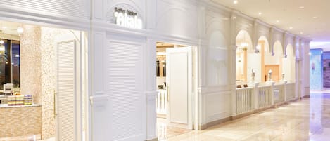 Pasillo de hotel con puertas cerradas, una zona de recepción y una alfombra estampada.