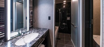A modern bathroom with a marble sink, a glass shower enclosure, and a walk-in shower.