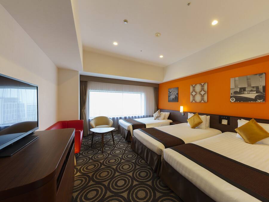 A hotel room with two beds, a TV, a desk, and a window with curtains.