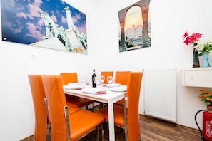 A dining area with orange chairs, a white table, and a white cabinet with a red fire extinguisher.