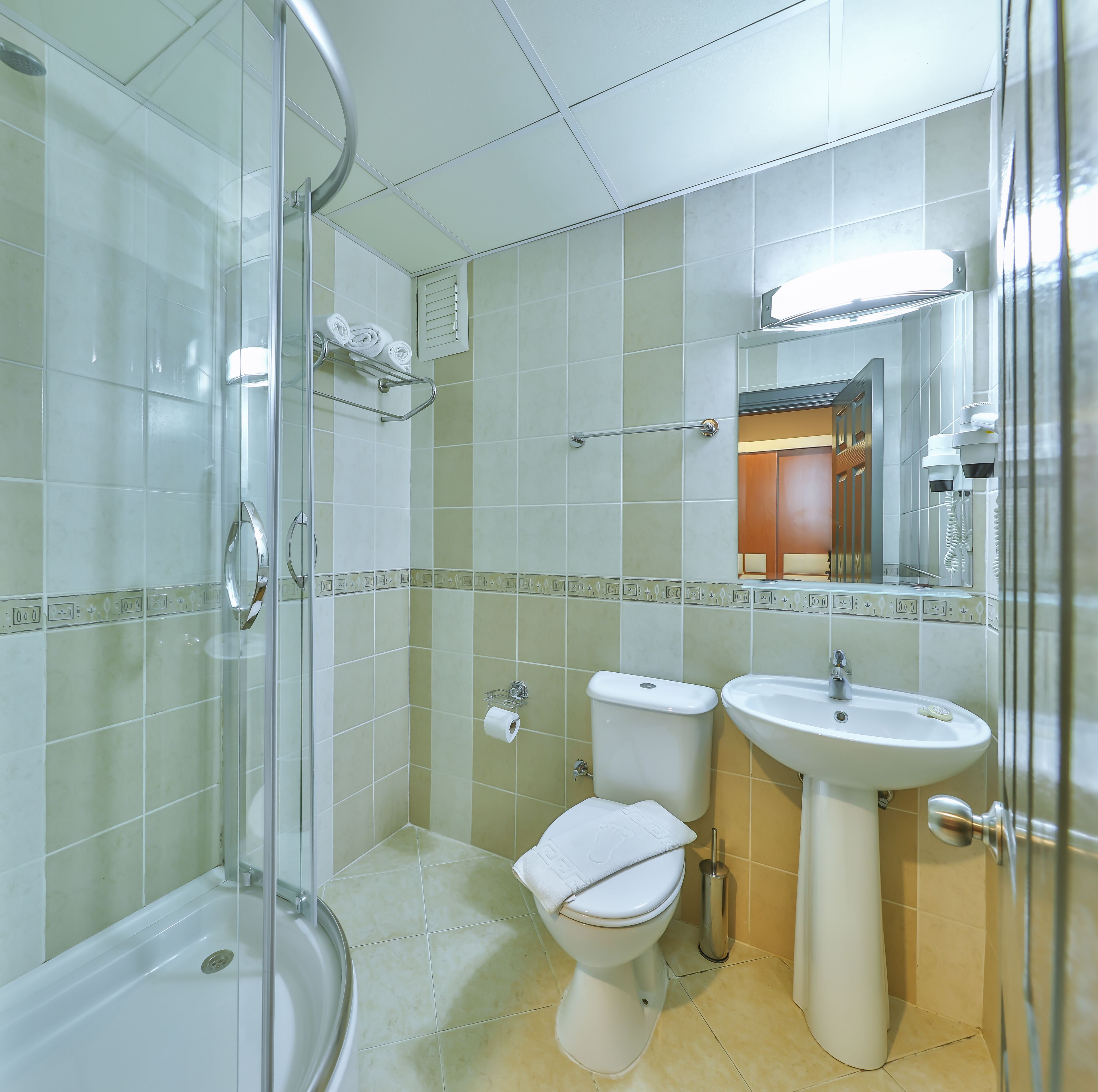 A bathroom with a glass shower enclosure, a toilet, and a sink.