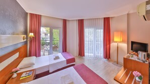 Quarto de hotel com duas camas, televisão, escrivaninha e varanda com cortinas vermelhas.