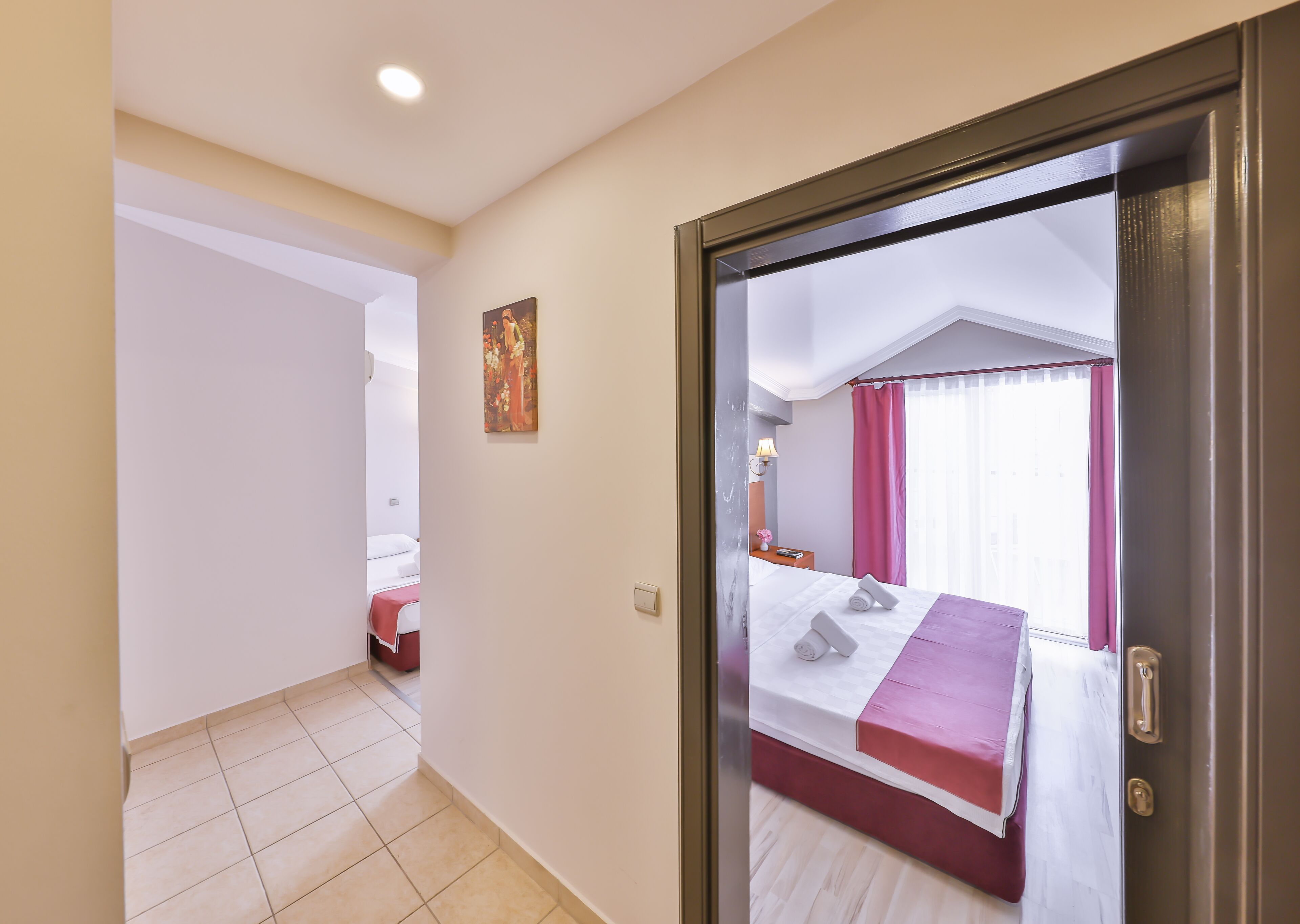 Una habitación de hotel con cama, mesita de noche, lámpara y un cuadro en la pared.