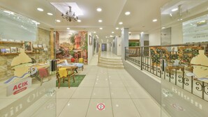 Amplio espacio interior con escalera, divisiones de vidrio y zona de comedor con mesas y sillas.