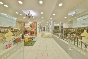 A spacious indoor area with a staircase, glass partitions, and a dining area with tables and chairs.